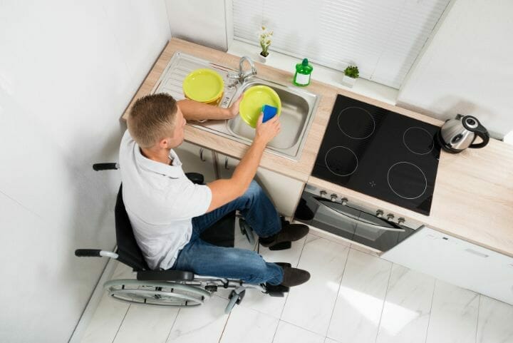 A man in a wheelchair using an accessible kitchen sink