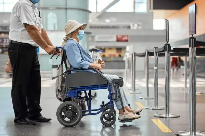 Airport staff assisting senior woman on wheelchair