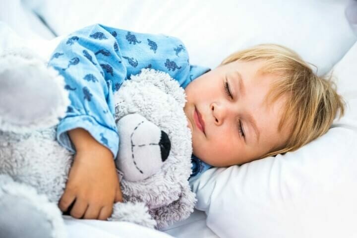 Cute boy sleeping while hugging his teddy bear