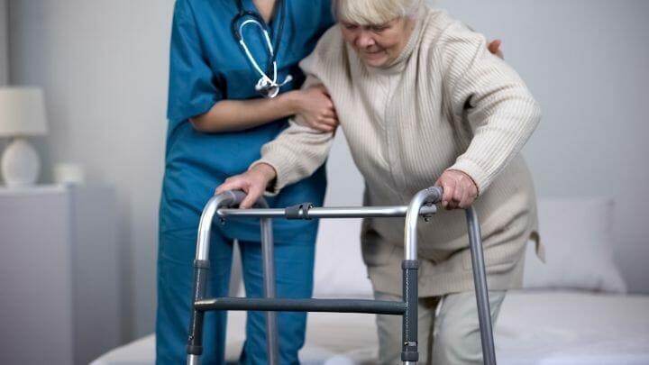Nurse assisting senior patient after hip replacement