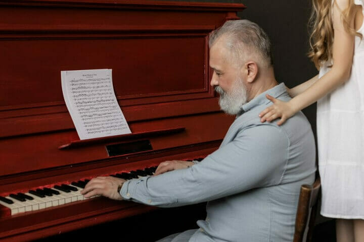 Old man playing piano for her ganddaughter
