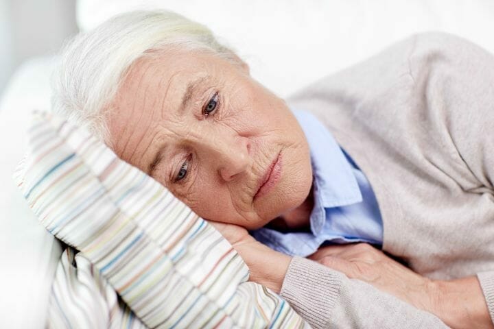 Sad senior lying on a pillow