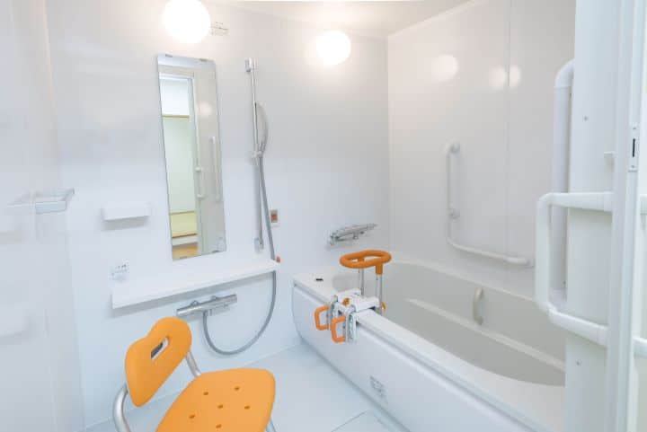 An adaptive bathroom with shower chair and grab bars in the right places