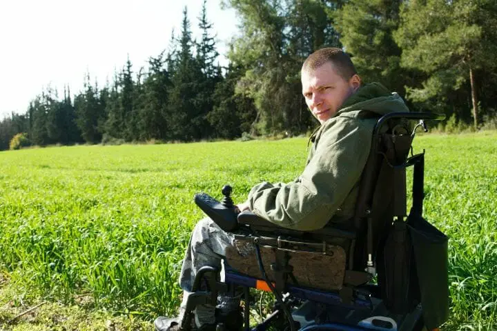 Young man on hos electric wheelchair in an open field
