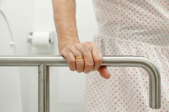 Hand of an elderly woman holding on a handrail