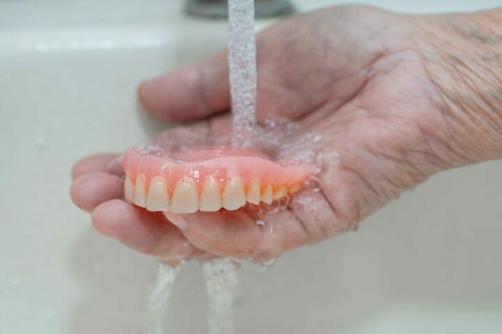 cleaning dentures thru running water