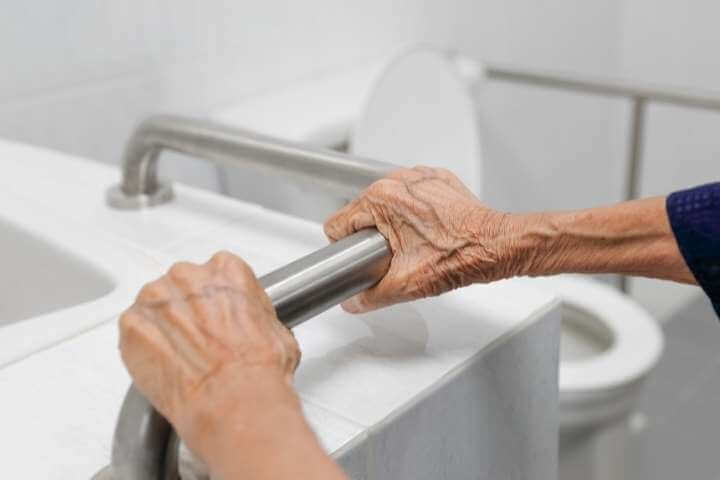 elderly woman holding grab bar inside the bathroom