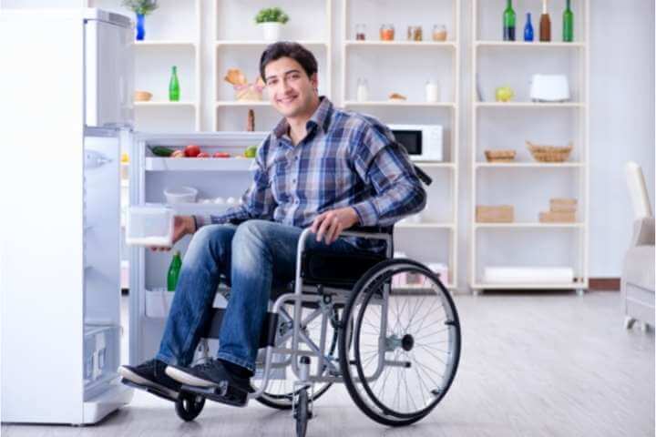man on wheelchair beside the fridge