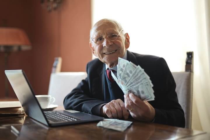 senior man working in his office holding some cash
