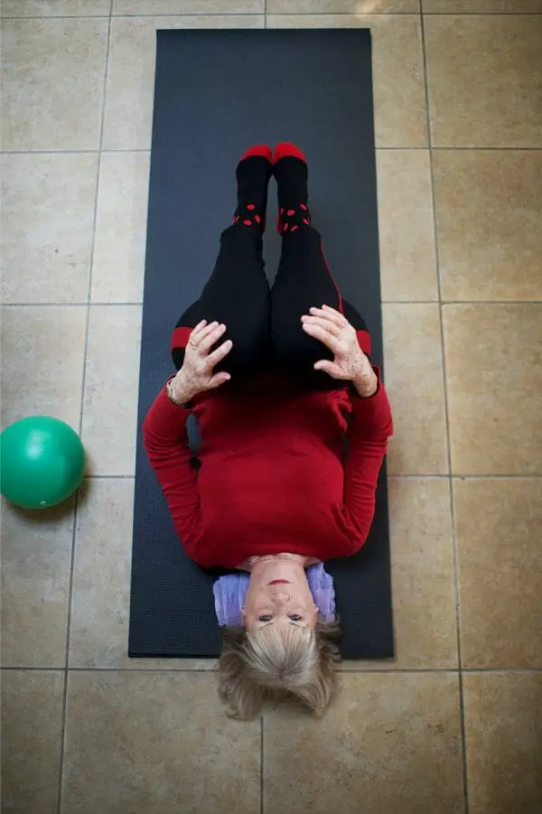 Senior woman doing lying down knee lifts