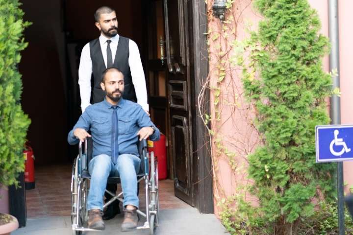 hotel staff assisting man on wheelchair